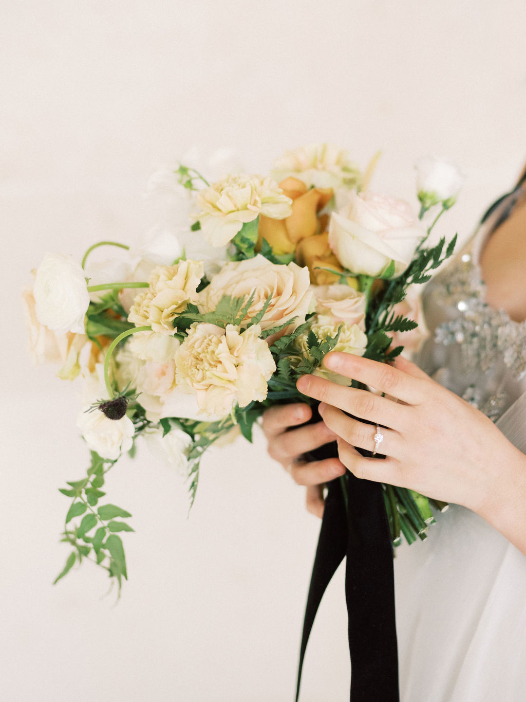 Woman holding flowers wearing three-stone ring