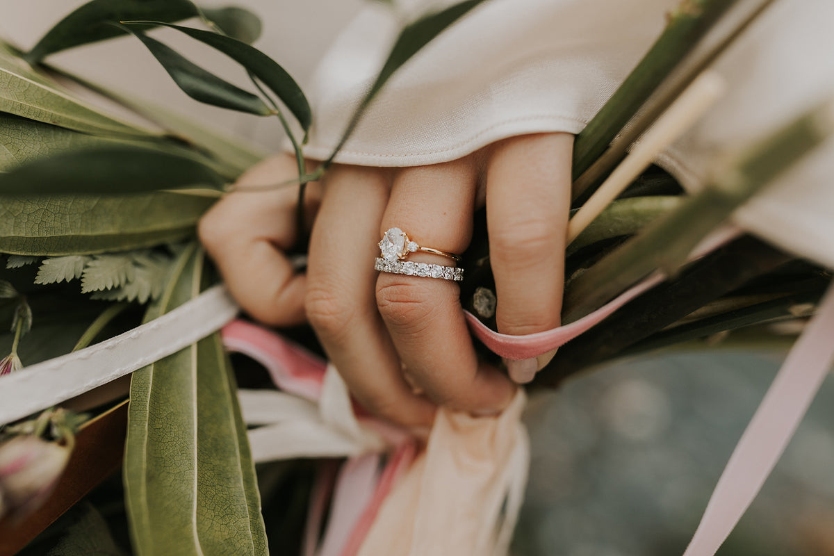 Woman wears diamond wedding band with three-stone engagement ring