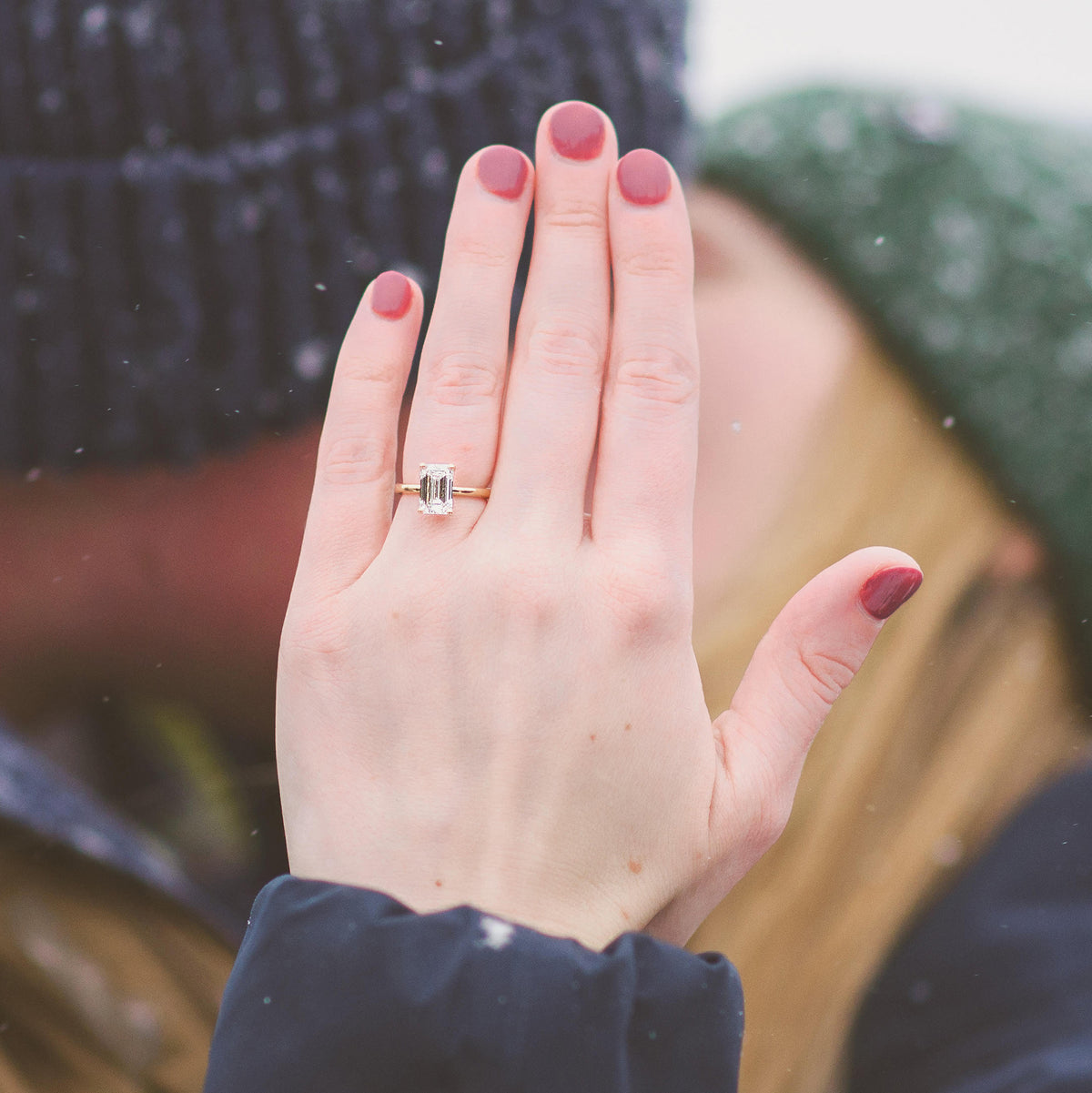 Yellow gold solitaire ring with emerald cut diamond on hand